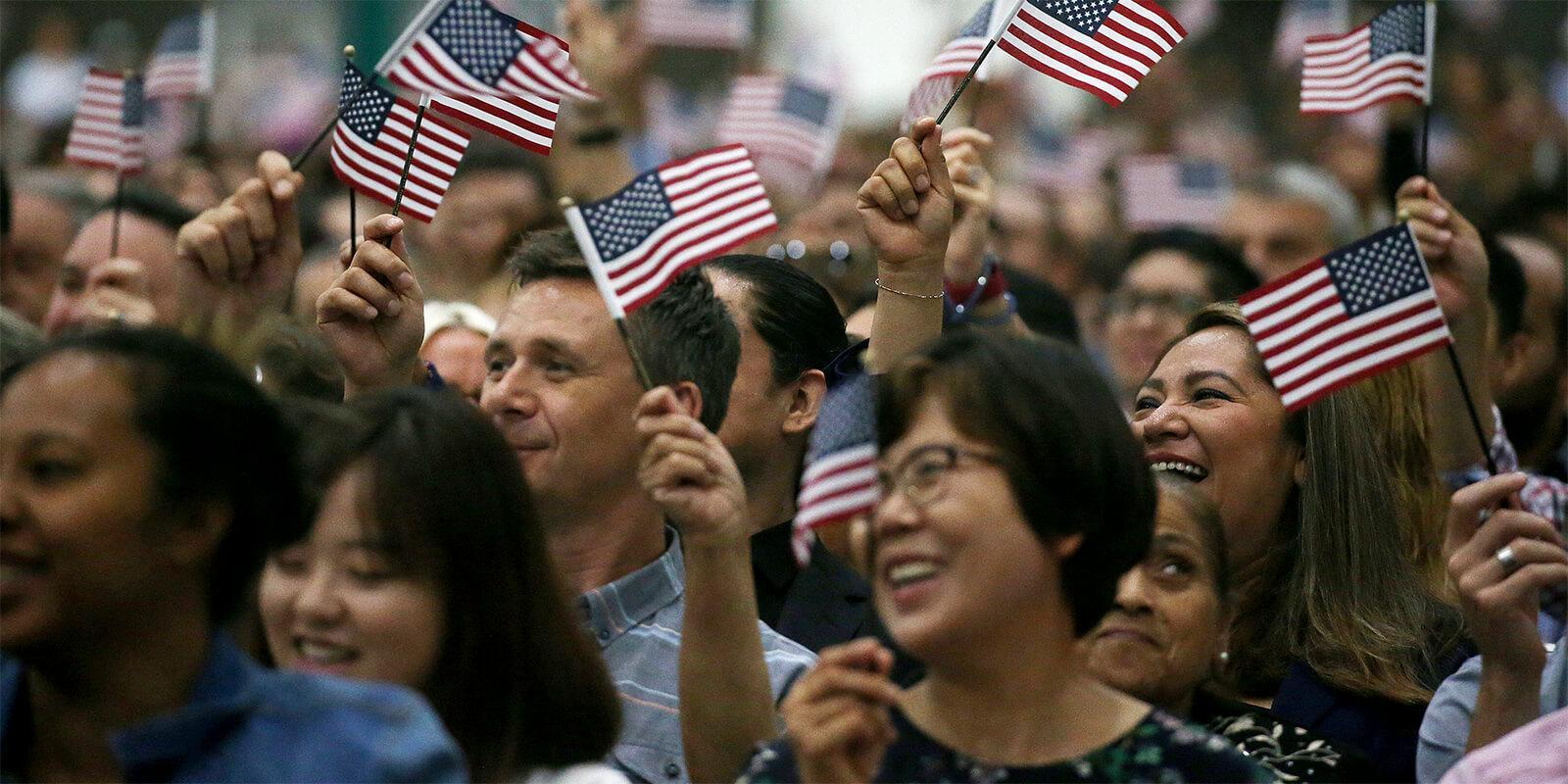 Diverse crowd of people waving small American flags